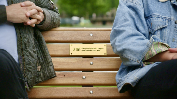 Op het bankje een plaquette met de tekst: 'Een goed gesprek begint met iemand echt zien'.