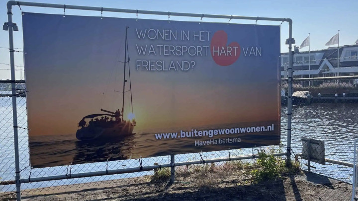 ‘Wonen in het watersport hart van Friesland?’, staat vermeld op dit reclamedoek aan de Rjochte Grou.