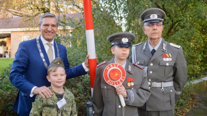 Buma poseert met een jonge soldaat en leden van de Deutsche Volkspolizei (Vopo's) bij de slagboom.