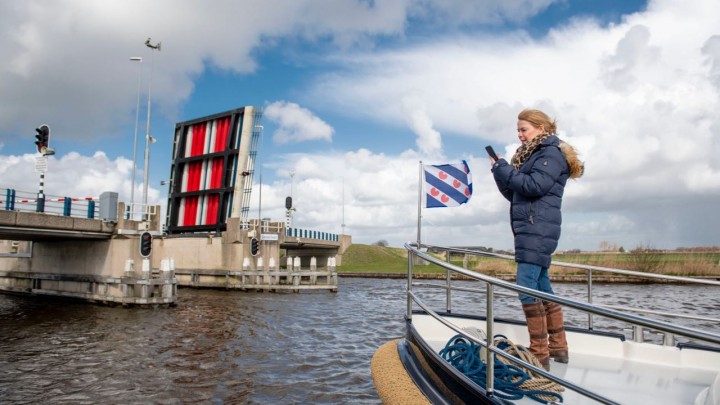 Gedeputeerde Avine Fokkens–Kelder opent de brug bij Langweer met de app.