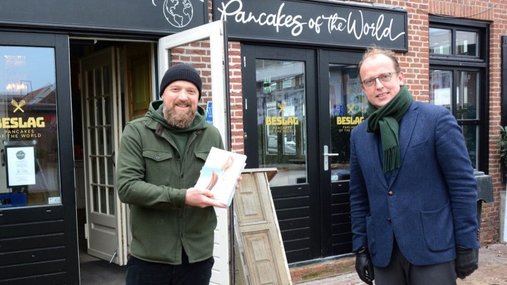  Johan Goslings, eigenaar van restaurant Beslag, ontving een exemplaar van 'Veelzijdig Grou' van wethouder Friso Douwstra. (Foto: Jikkie Piersma)