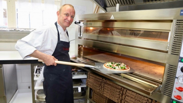 Marco Hofstede schuift een vers bereide pizza in de oven. (Foto: Press4All)