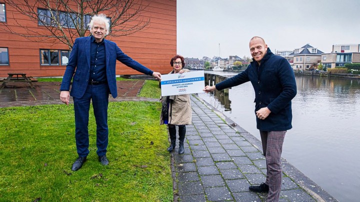 Annet van der Hoek, lid dagelijks bestuur Wetterskip Fryslân, overhandigt de aquathermie-vergunning aan wethouder Hein de Haan (rechts) van de gemeente Leeuwarden en directeur Pieter Hofstra (links) van de FUMO. (Foto: Daniël Hartog).